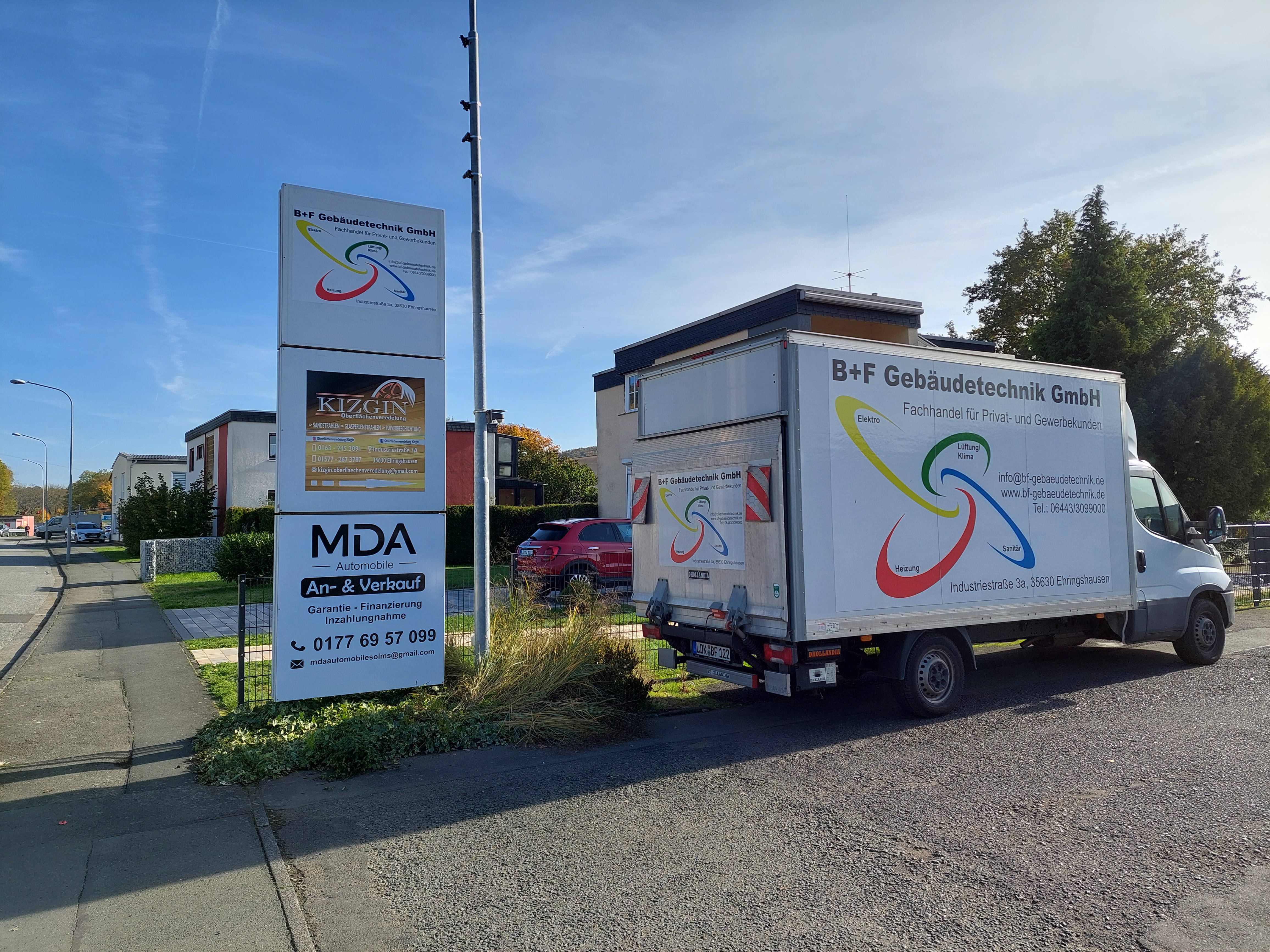 Straßenansicht von B+F Gebäudetechnik in der Industriestraße 3a in Ehringshausen, erkennbar am Firmenschild und Lieferwagen